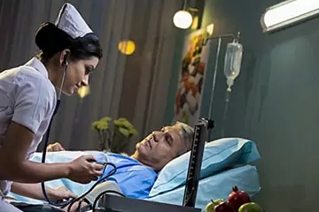 Nurse monitoring an elderly patient receiving a drip at home