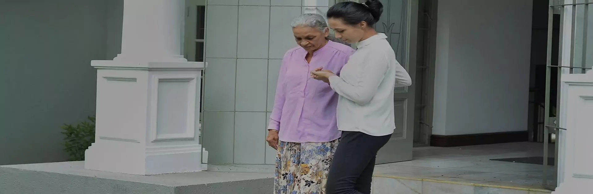 Caregiver walking with an elderly person outside their home